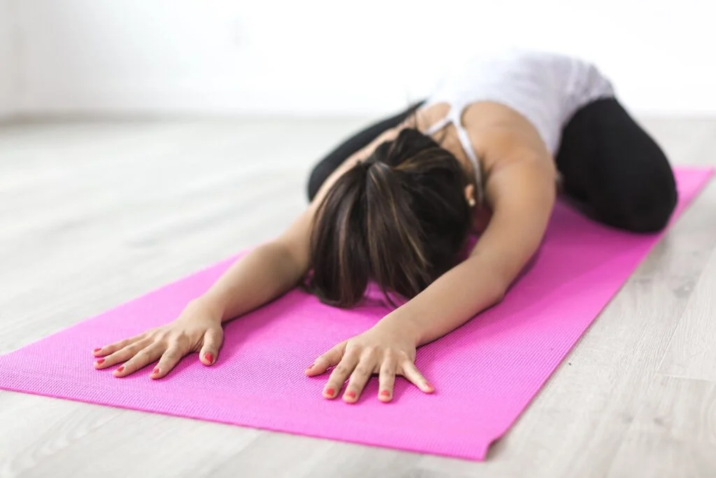 Child's pose yoga woman an a yoga mat. Self-care ideas.