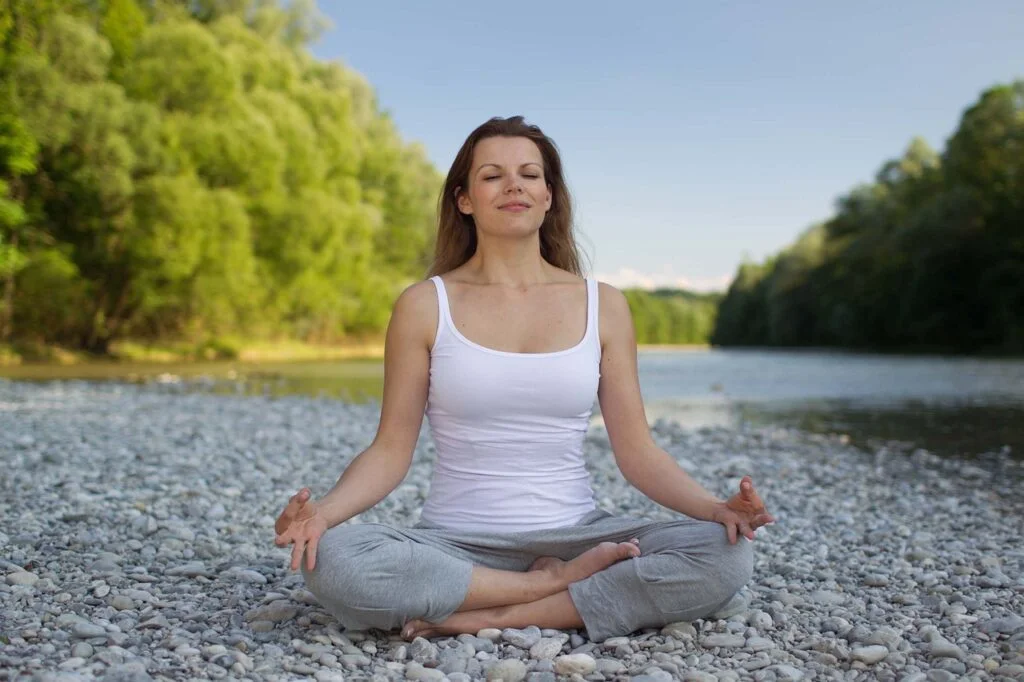 A woman meditating and breathing outdoors.